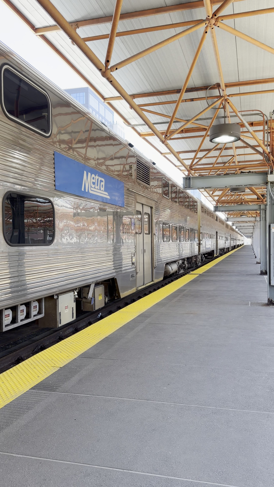 A silver Metra train beside a covered platform